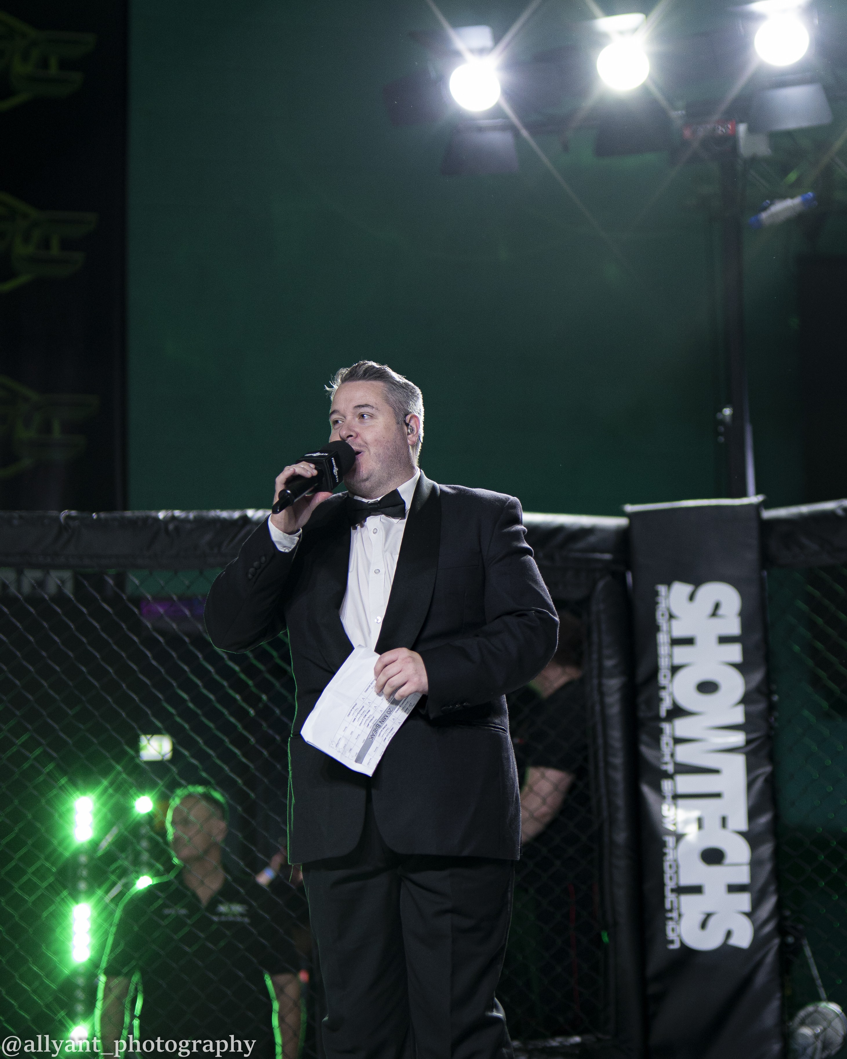 Jonathan Millard announcing at a Showtechs MMA event under dramatic green lights
